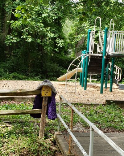 purple child-size coat on an empty playground's railing. 